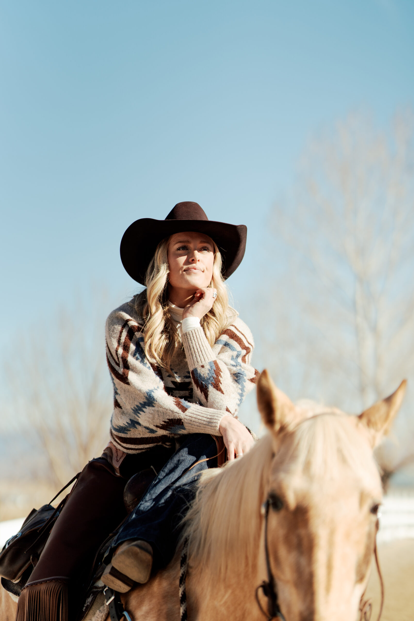 Girl sitting relaxed on her horse, enjoying the peaceful outdoors with a calm and confident posture.