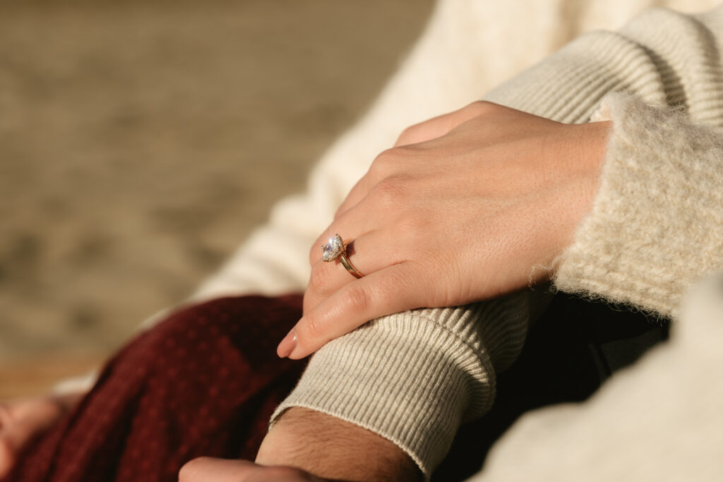 Close-up of couple holding hands with ocean backdrop