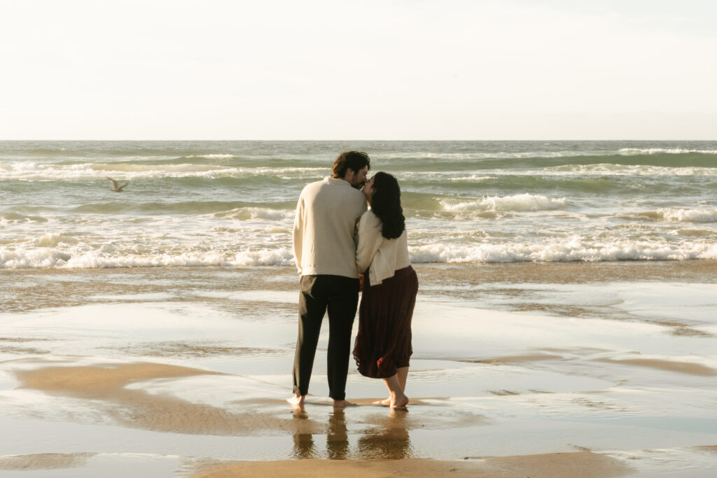 Couple standing close together by ocean water