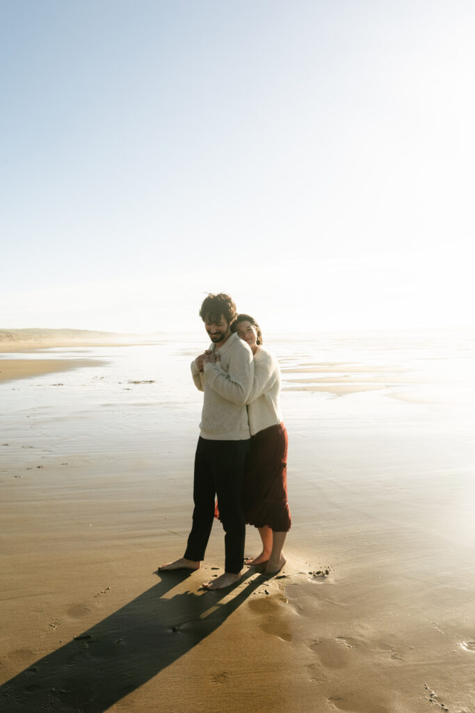 Couple standing close together by ocean water