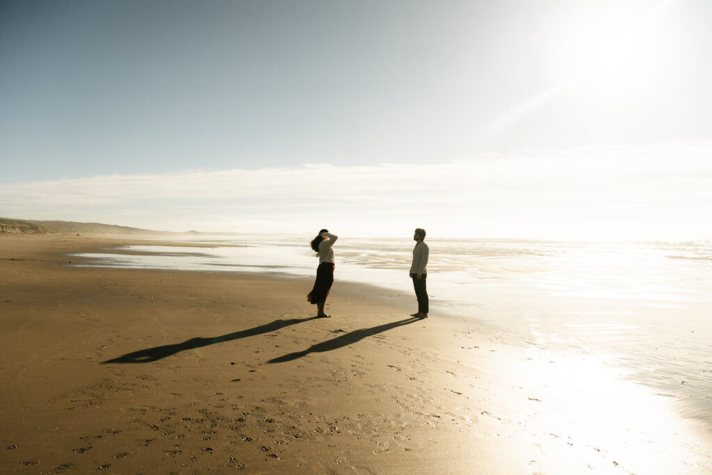 Couple standing close together by ocean water