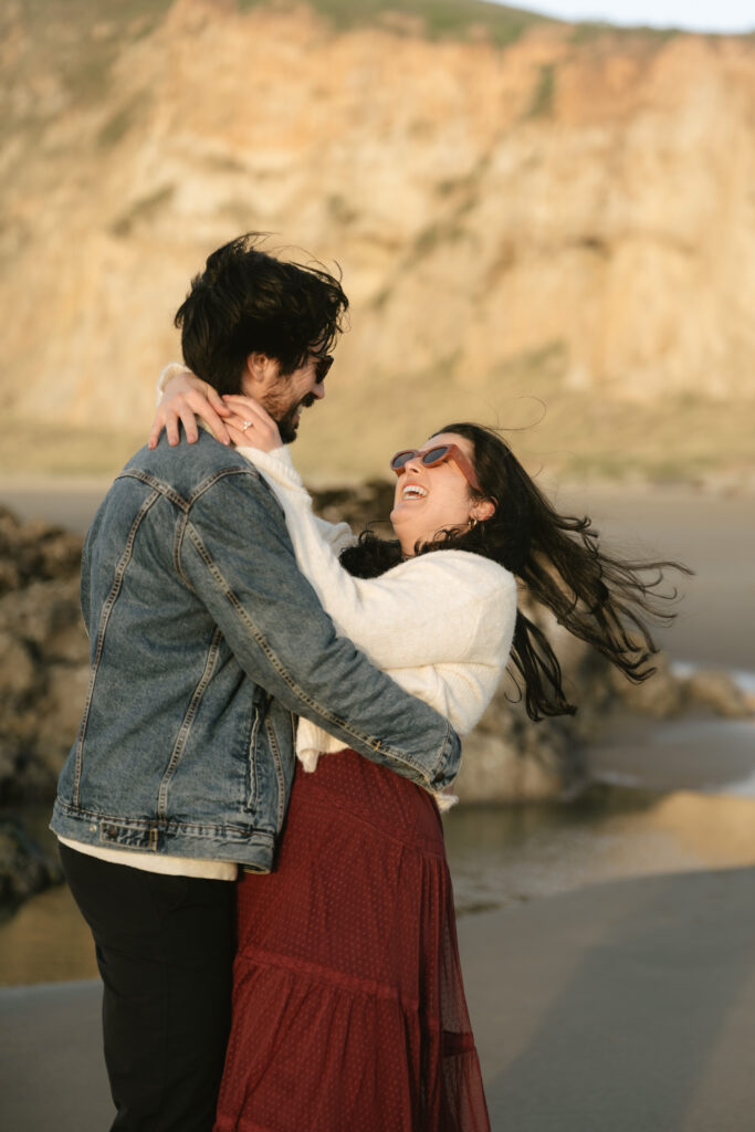 Man dipping woman playfully on sandy beach