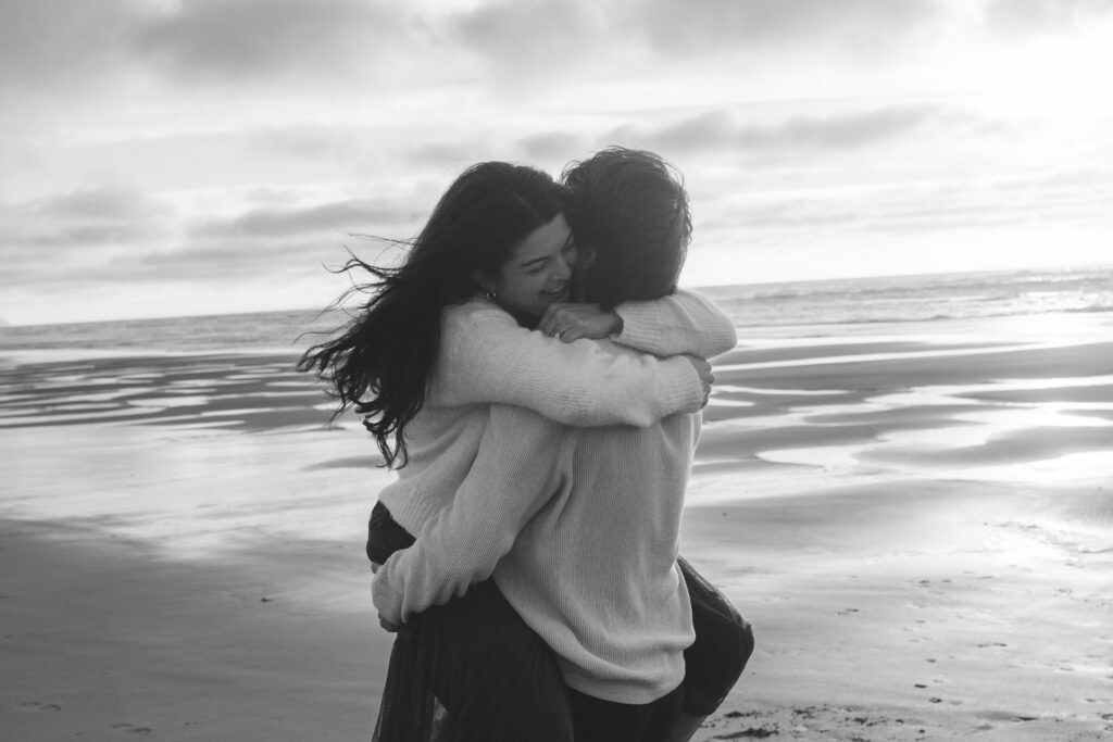 Black and white image of couple hugging on the beach