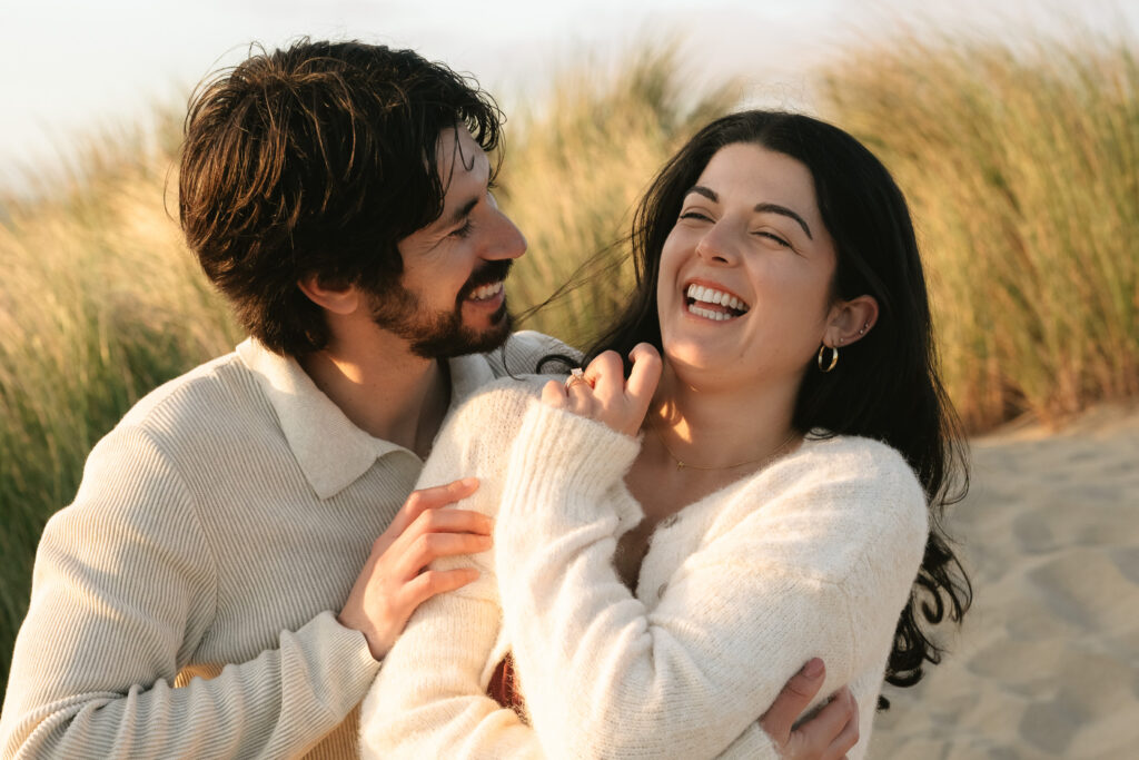 Playful couple laughing together near coastal cliffs