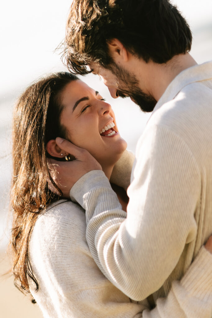 Couple laughing together in warm sunset light on the beach
