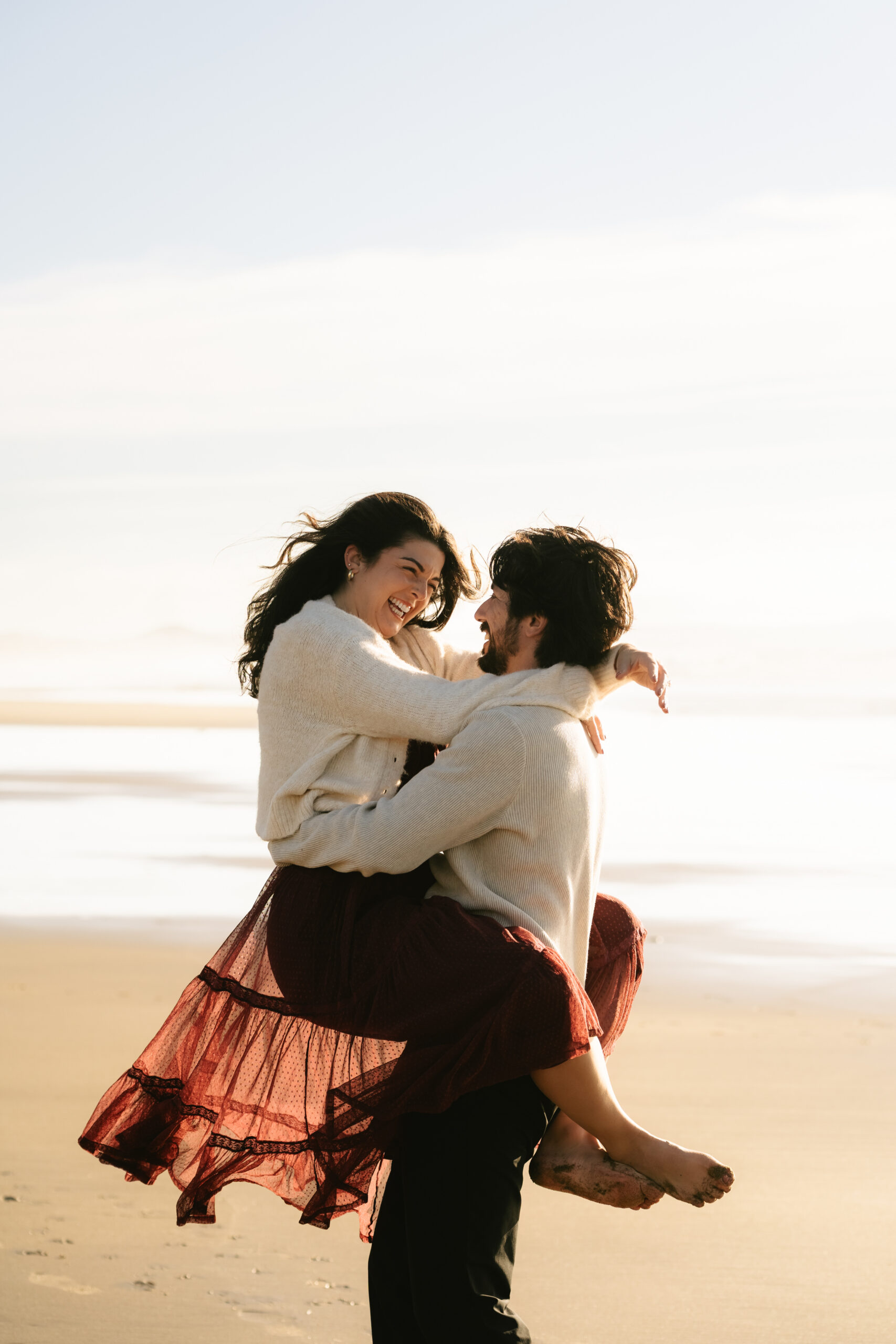 Couple embracing on the beach with wind in her skirt