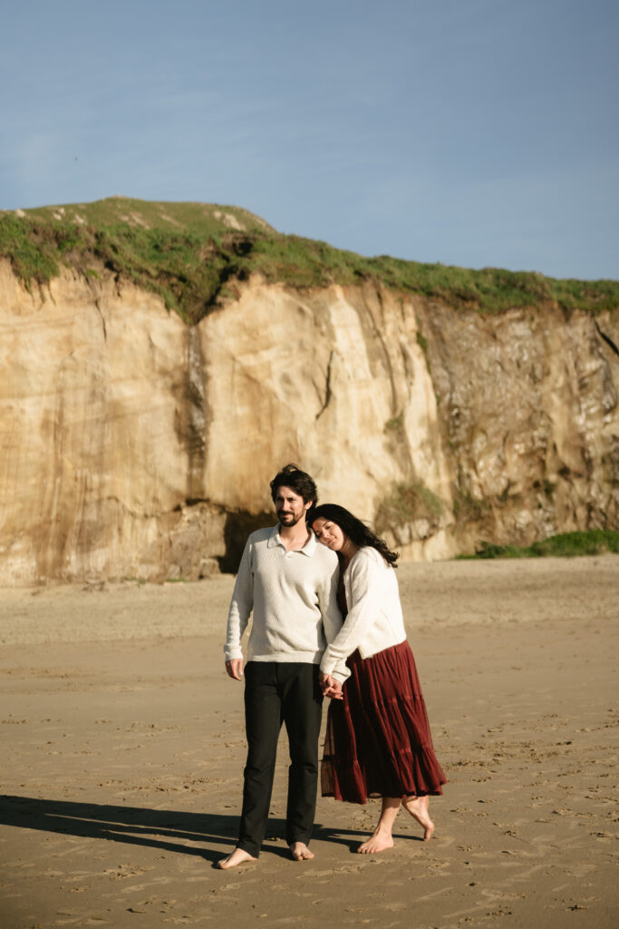 couple embracing on the beach with cliffs behind them