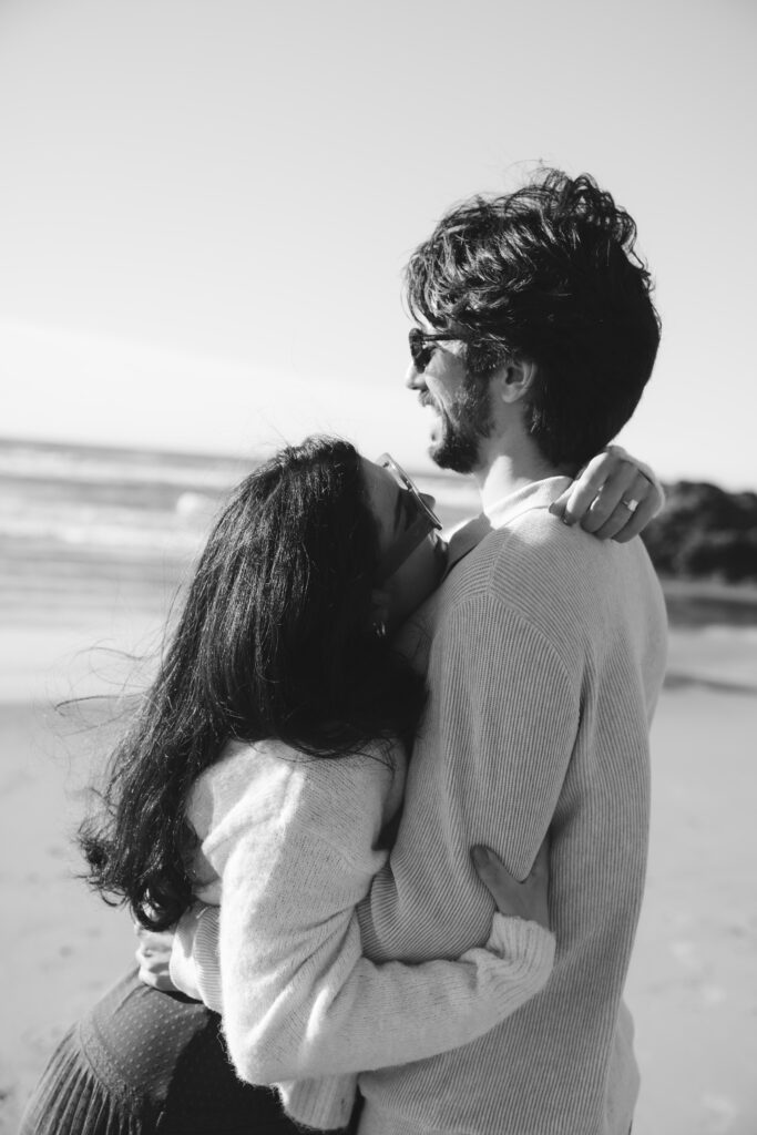 Black and white image of couple walking along the beach together