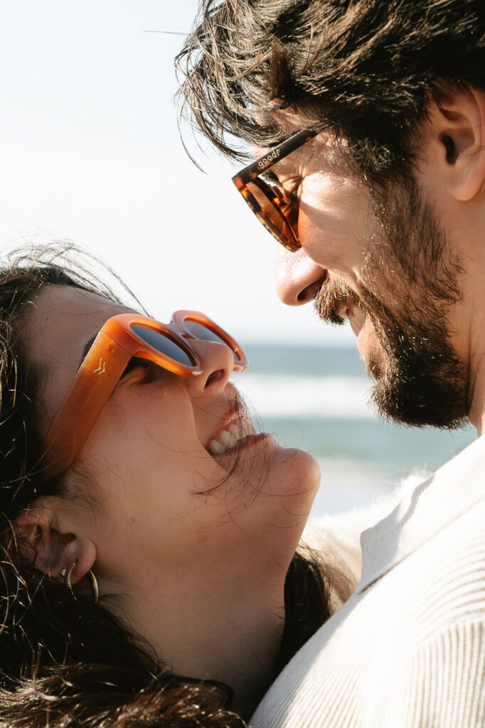 close up of couple smiling at one another with sunglasses