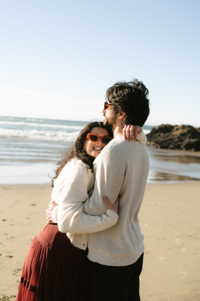 Couple embracing closely with soft ocean horizon behind them
