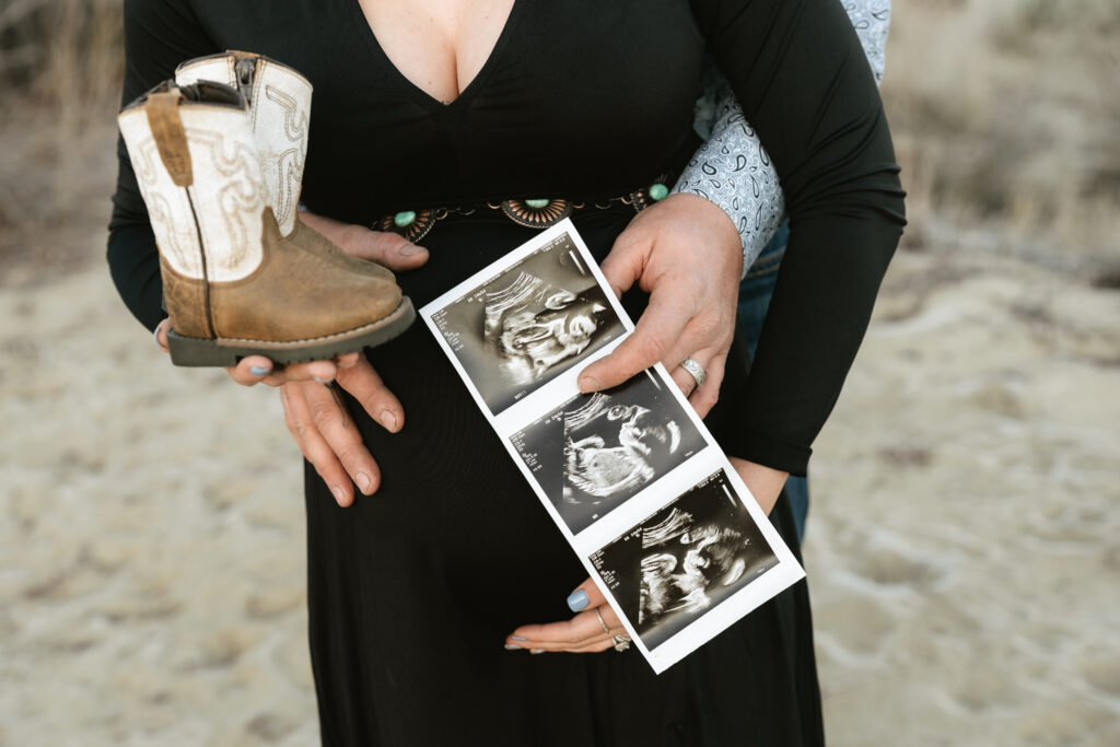 Man and woman holding baby cowboy boots and sonogram