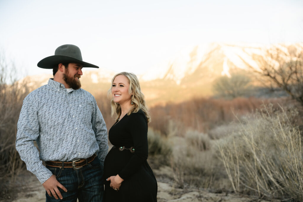 Man and pregnant woman holding hands with mountain view