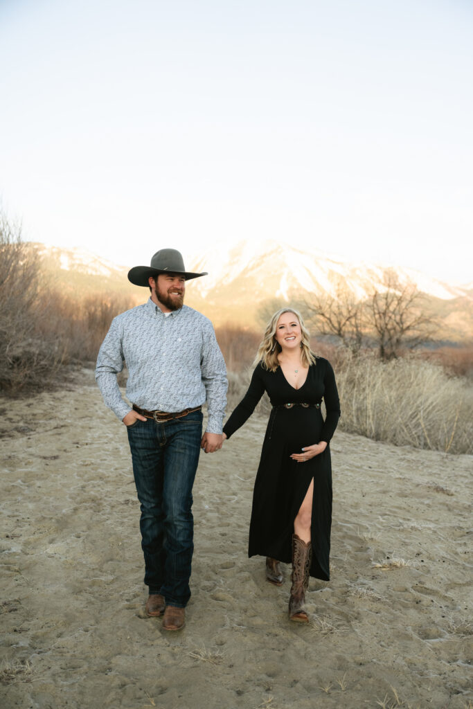 Man and pregnant woman walking with mountain view behind them