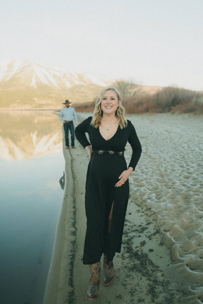 Film photo of pregnant woman walking alongside lake with husband behind her