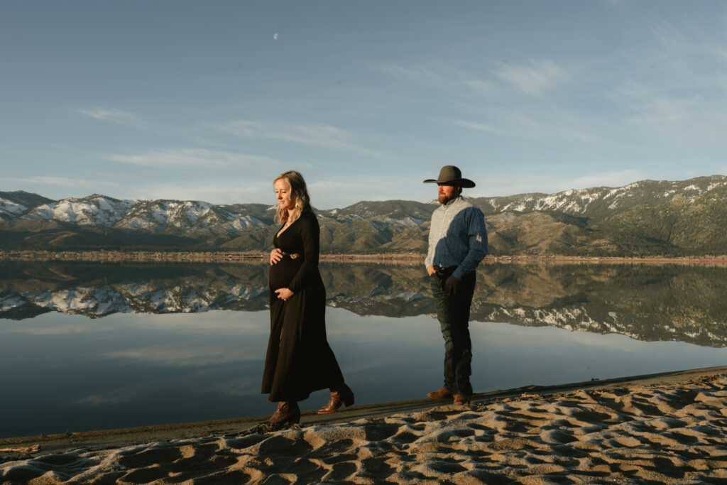 pregnant woman walkinga way from cowboy at sunrise surrounded by mountains