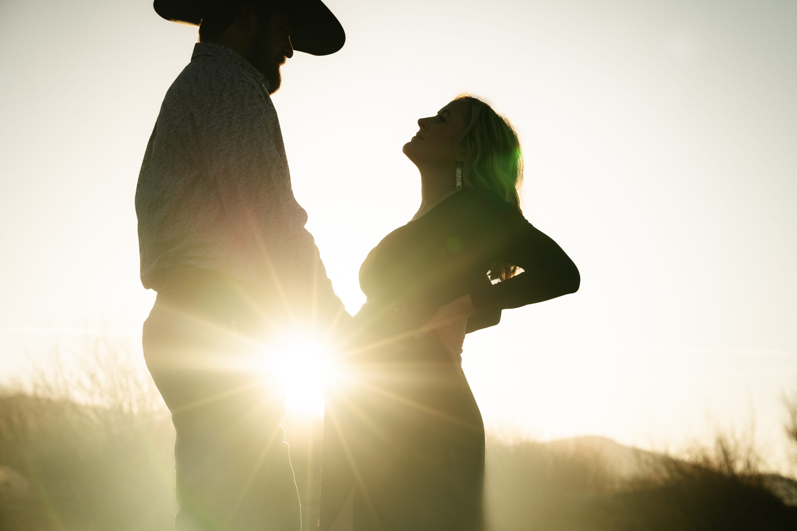 film photo of cowboy holding pregnant wife's belly in sunlight