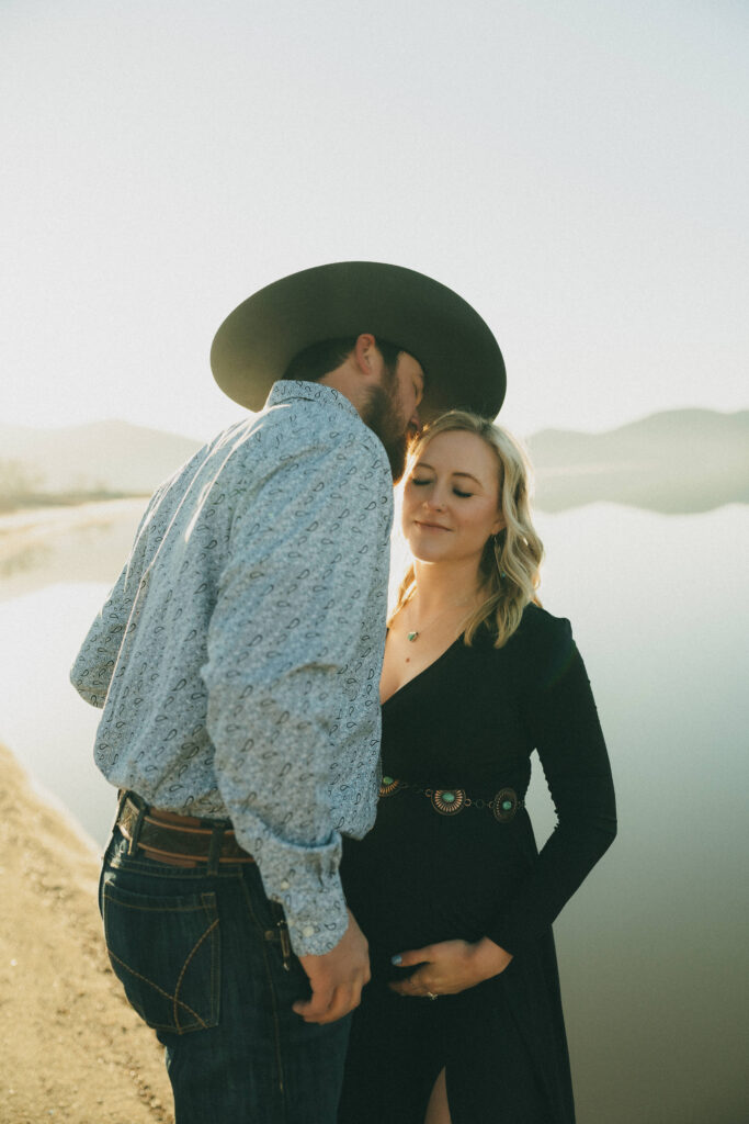 Film photo of cowboy kissing pregnant womans forehead